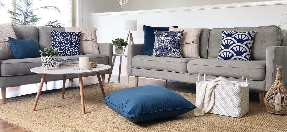 Living room decorated with different kinds of cushions in navy blue and cream colours.