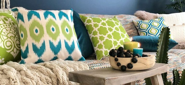 Green and blue patterned cushions to accentuate the blue walls and the multi coloured sofa.