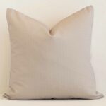 A lovely large sand cushion cover arranged in front of a white wall. The solid-colour style complements the outdoor material.