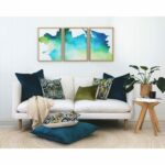 Olive and teal cushions and wall art in Ikat pattern against a white wall and sofa.