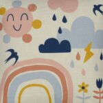 Close-up image of colourful kids cushion with rainbow, clouds and flowers print