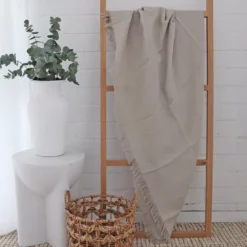 A white living room with a stone linen throw hanging on a wooden rack.
