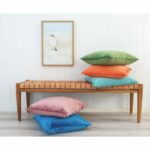 Colourful velvet cushion covers on wooden seat against a wall art