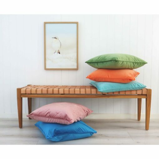 Colourful velvet cushion covers on wooden seat against a wall art