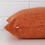 Horizontal edge view of front and back panels of a linen cushion in a square size and with rust colouring.