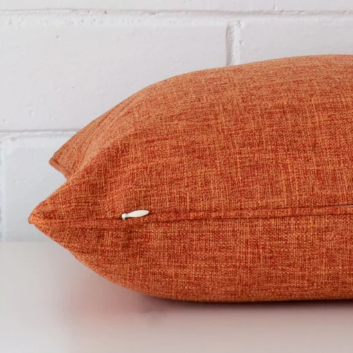 Horizontal edge view of front and back panels of a linen cushion in a square size and with rust colouring.