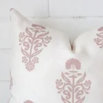 A zoomed view of this linen pink cushion’s corner that shows a magnified view of its patterned design and its square size.