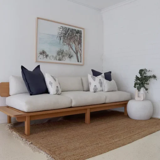 A cozy living room with a set of 5 sofa cushions under a hanging framed wall photo.