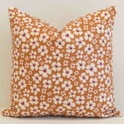 Amora ditsy floral cushion with white flowers on warm orange background.