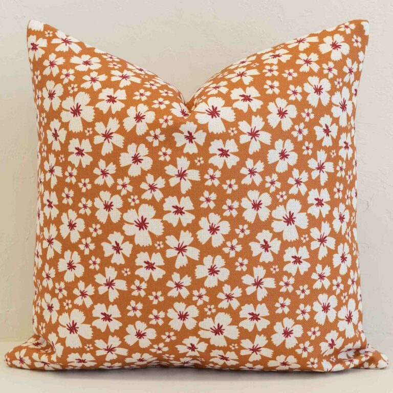 Amora ditsy floral cushion with white flowers on warm orange background.