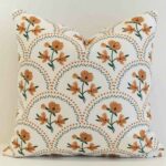Amora floral scallop cushion with orange flowers and green geometric pattern.