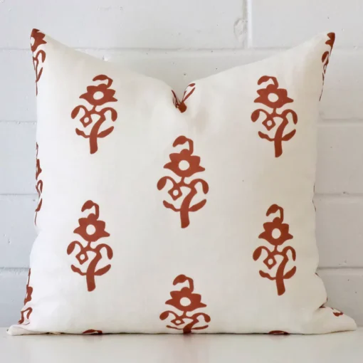 A bold patterned linen cushion in a sleek square size with a terracotta tone of colour.