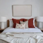 A set of 4 bed cushions arranged on a bed between two bedside tables.