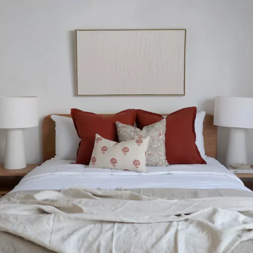 A set of 4 bed cushions arranged on a bed between two bedside tables.