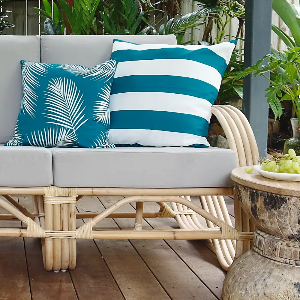 A back patio scene with grey seating that has some teal outdoor cushions on it.