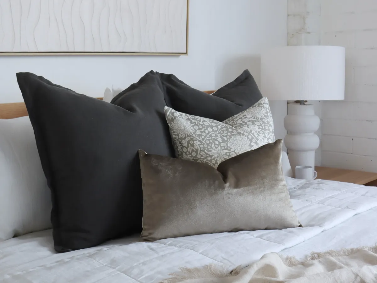 A bedroom with urban modern colours styled on a bed.