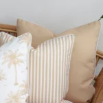A focused view of a set of 3 beige outdoor couch cushions. The shot displays details of their material and color.