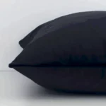 A close up image of this solid-coloured square cushion. The image shows details of its velvet fabric and black colour.