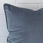 Extreme close up of a large blue grey cushion. The velvet fabric is shown with a much higher degree of detail.