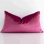 A pretty solid colour velvet cushion cover is shown against a white wall. It features a rectangle shape and a blush colour finish.
