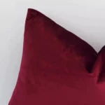 A magnified shot of a solid colour velvet cushion cover in a rectangular shape and a burgundy colour.