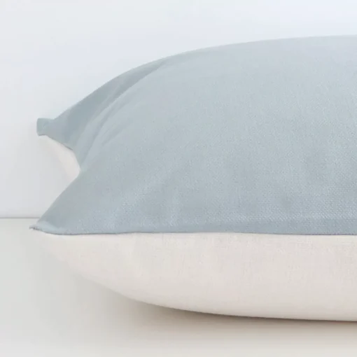 A solid-coloured soft teal cushion cover is laid flat. This angle shows the side of the linen fabric and its large size.