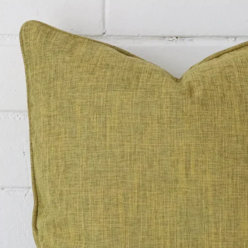 Close up image of top corner of this olive cushion. This shows the linen fabric and sqaure shape up close.