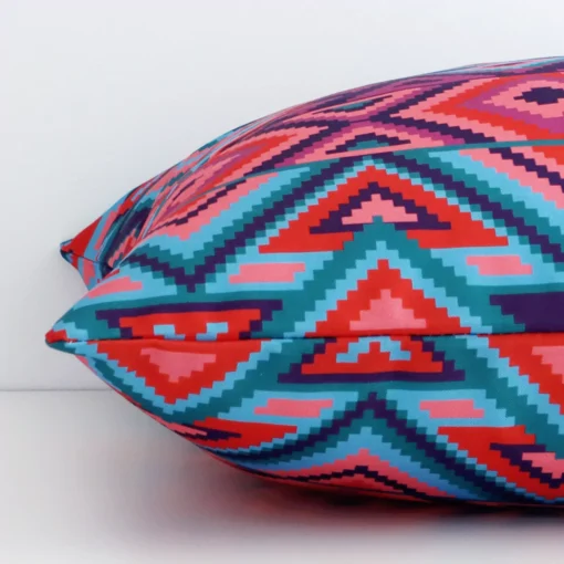Geometric cushion cover laying sideways against white wall. The square size and outdoor material are shown highlighting the seams.