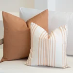 A set of 2 Claybourne outdoor cushions displayed on a white sofa.