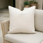 Cream waterproof cushion on woven outdoor chair with tiled patio background.