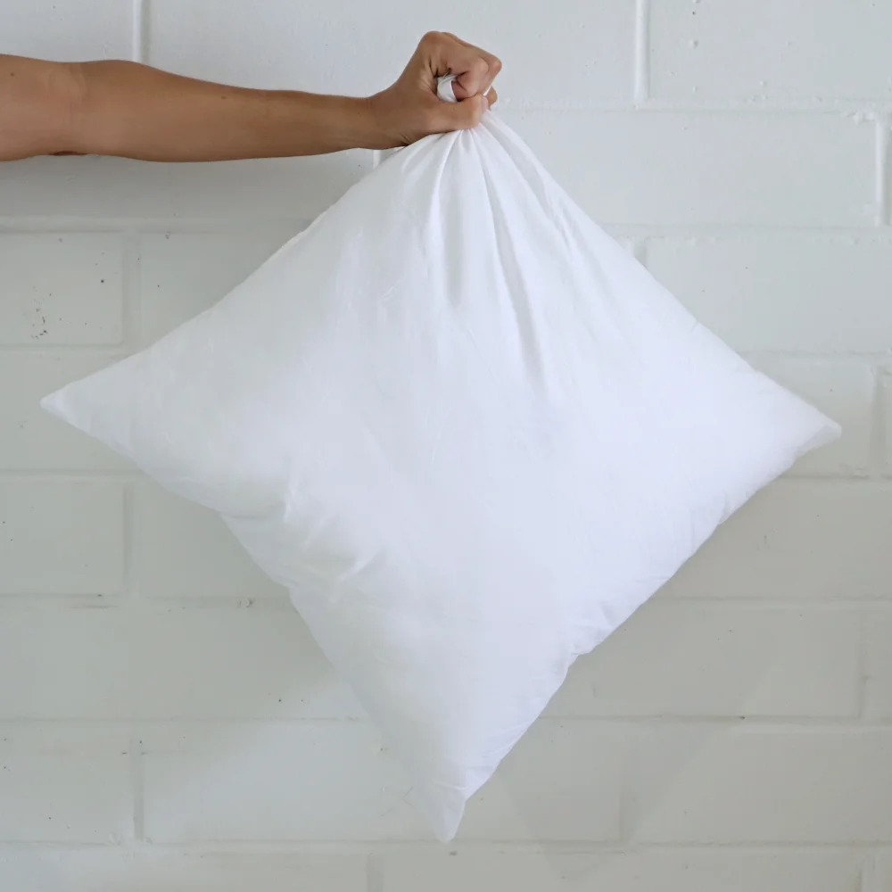 A cushion insert inner is being held by its corner in the air.