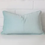 Duck egg cushion leans elegantly against a brick wall. It has been crafted from a high quality velvet material and has a square shape.