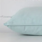 Horizontal edge view of front and back panels of a velvet cushion in a rectangle size and with duck egg colouring.
