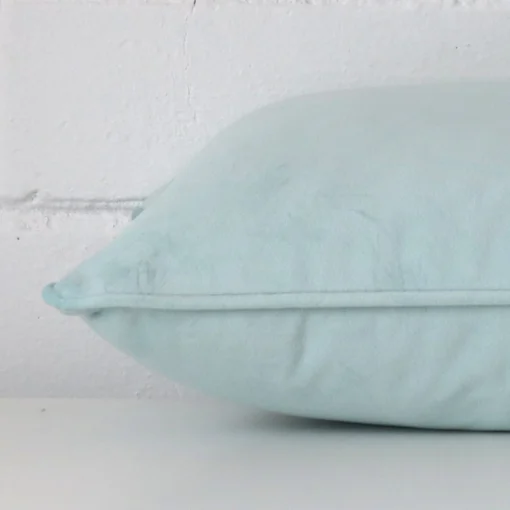 Horizontal edge view of front and back panels of a velvet cushion in a rectangle size and with duck egg colouring.