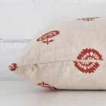 The seams of this linen rectangle cushion cover in rust are shown. The image shows the floral design and how the panels are attached.