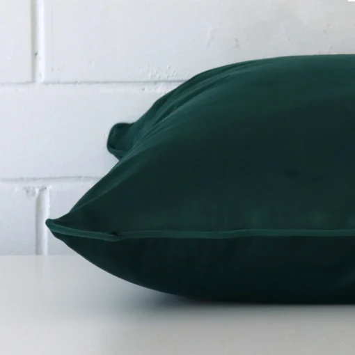 Enlarged image of the side of this emerald green velvet cushion. The angle highlights the edge of its large design.