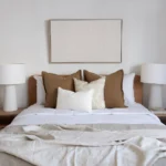 A wooden bed between two lampshades with a set of 4 Eve bed cushions styled on it.
