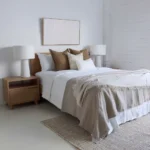 The set of 4 Eve bed cushions complements the colour of the wooden bed in a white bedroom.