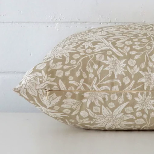 A floral cushion cover is laid flat. This angle shows the side of the linen fabric and its rectangle shape.