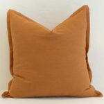 Ginger linen cushion with rich warm orange tone and woven texture.