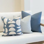 A white sofa with 3 horizon blue outdoor cushions arranged neatly on it.