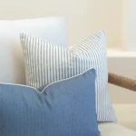 2 horizon blue outdoor cushions are displayed on a white sofa.