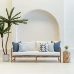 A wooden sofa is styled with a set of 5 horizon blue outdoor cushions.