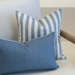 2 horizon cove outdoor cushions are displayed on a white sofa.