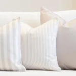 A white couch with a set of 3 outdoor couch cushions in a horizon sage colour.