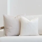 White living room scene with 2 horizon sand outdoor cushions arranged on a sofa.
