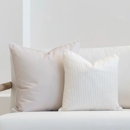 White living room scene with 2 horizon sand outdoor cushions arranged on a sofa.