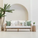 Green cushions arranged on outdoor sofa with palm and check patterns.