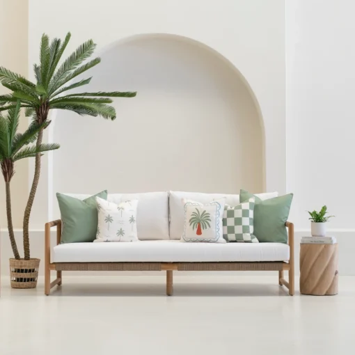 Green cushions arranged on outdoor sofa with palm and check patterns.