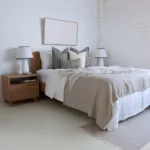 An airy white bedroom with 4 designer cushions from the Jude set sitting on a wooden bed.